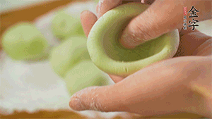 將均分的艾草面團(tuán)搓成圓，挖一個(gè)窩，放入餡心，再搓成圓。