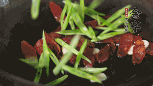 先后下香腸片、四季豆絲均勻翻炒，加適量清水燜煮一下。