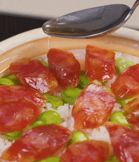 大米出現(xiàn)小孔時開蓋放香腸，往鍋邊淋入少許油，再燜煮8~10分鐘左右。