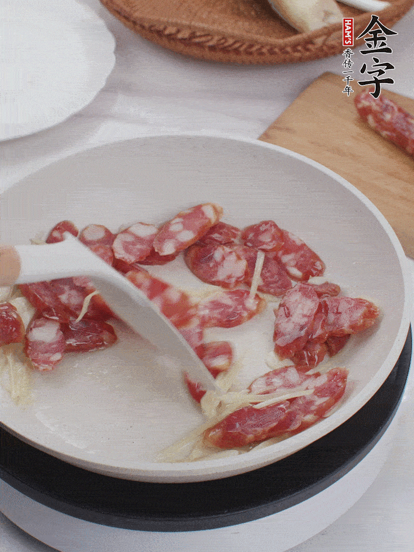 油溫3成熱時(shí)，下姜絲、蒜片、香腸炒出油脂。