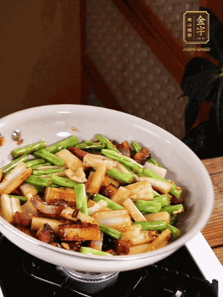 油熱下蒜末、干辣椒、醬肉煸炒出香味，依次下藕條、豆角翻炒均勻